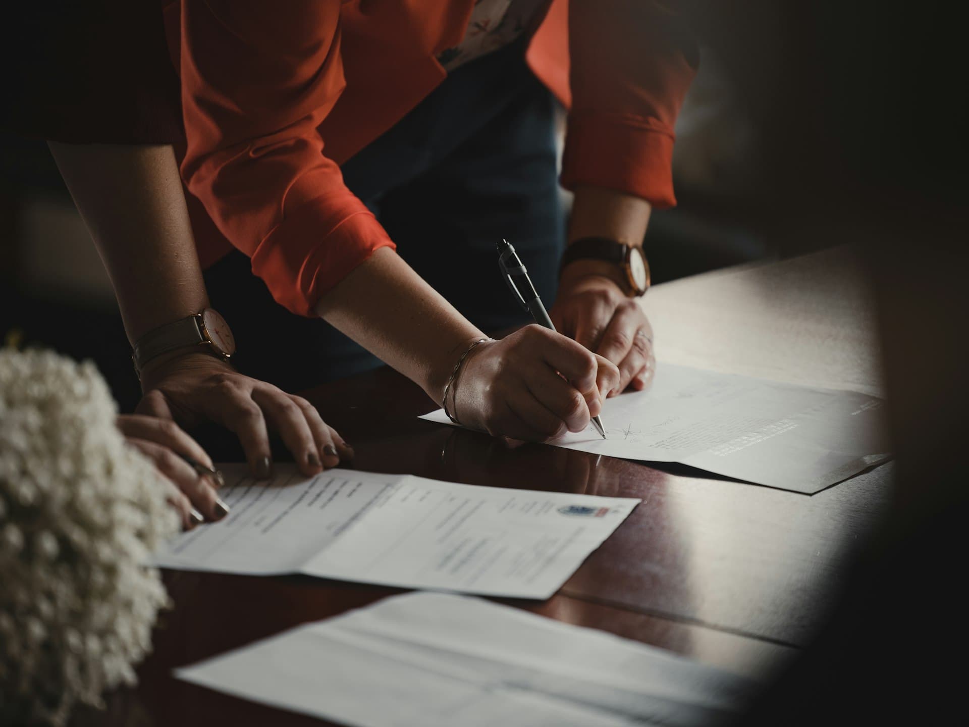 Person signing a document with a pen